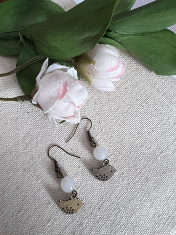 Boucles d’oreilles breloque oiseau bronze et bille de verre blanche Comme un ange