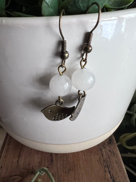 Boucles d’oreilles breloque oiseau bronze et bille de verre blanche Comme un ange