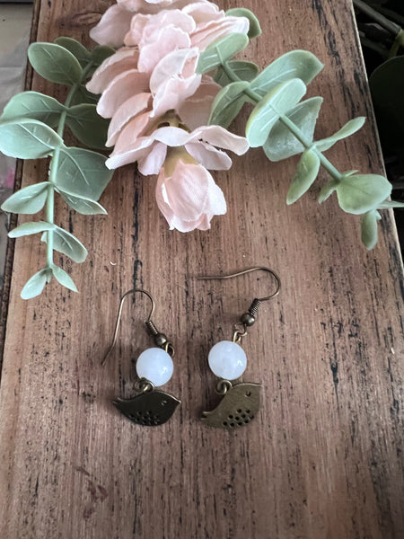 Boucles d’oreilles breloque oiseau bronze et bille de verre blanche Comme un ange