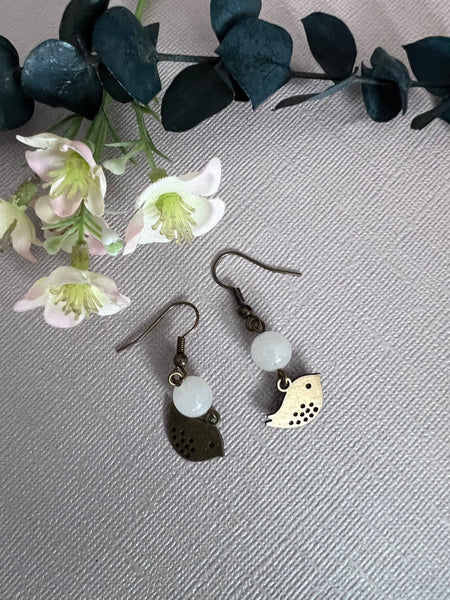 Boucles d’oreilles breloque oiseau bronze et bille de verre blanche Comme un ange