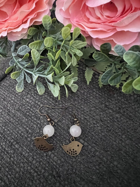 Boucles d’oreilles breloque oiseau bronze et bille de verre blanche Comme un ange